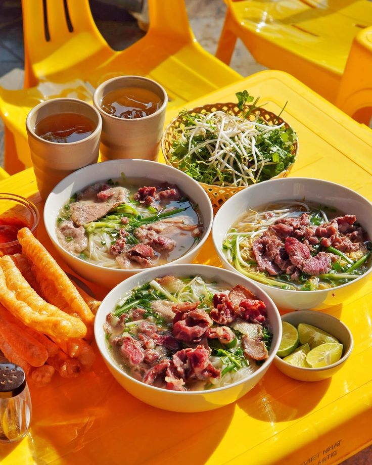 Bowls of Vietnamese noodle soup on a yellow table